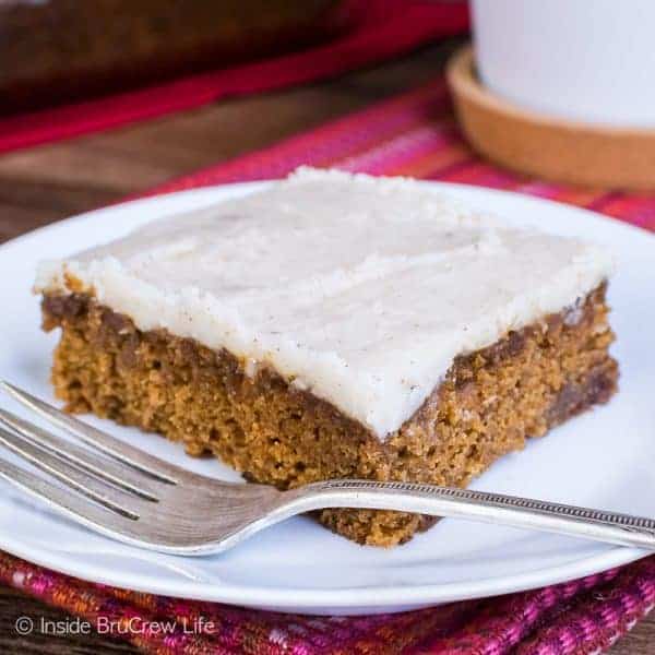 A square of apple butter cake with vanilla bean frosting on a white plate.