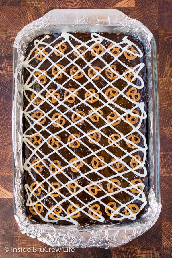 Overhead picture of caramel brownies topped with chocolate and little pretzels.