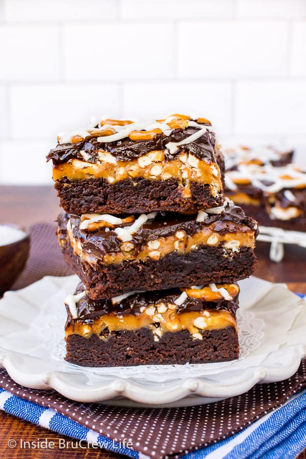 Three salted caramel brownies stacked on a white plate.