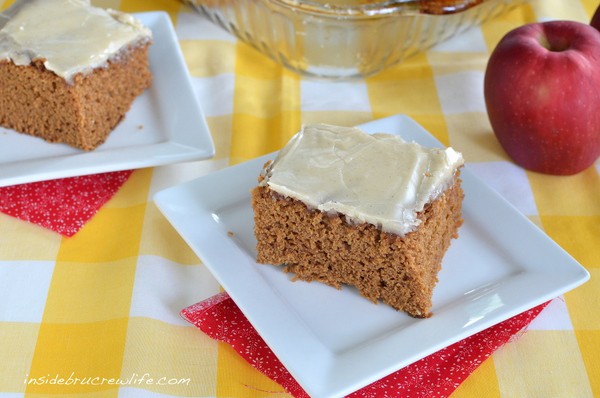 Two white plates with squares of glazed apple butter cake on them.