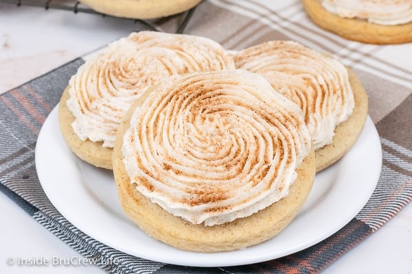 A white plate with three frosted churro cookies on it.