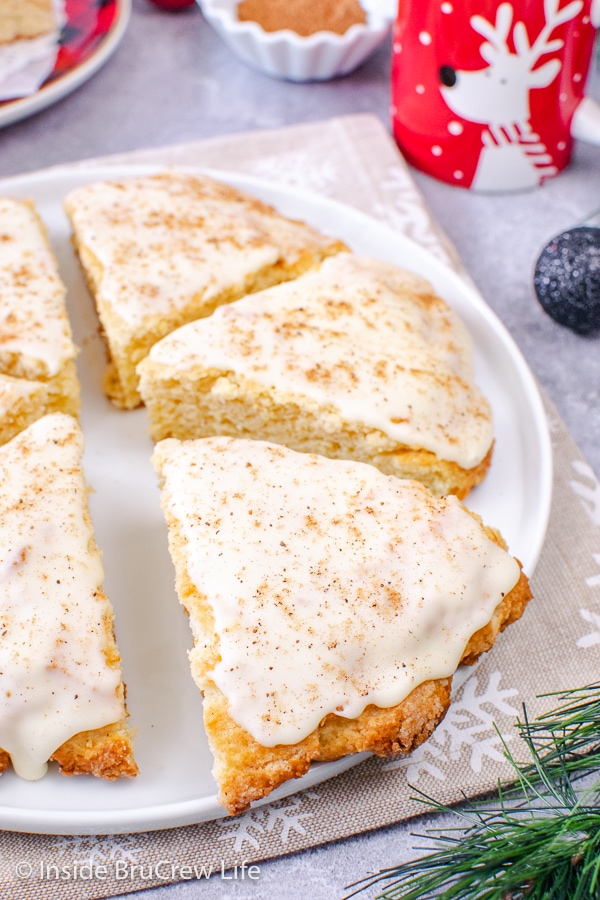 A white plate with flakey glazed eggnog scones on it.