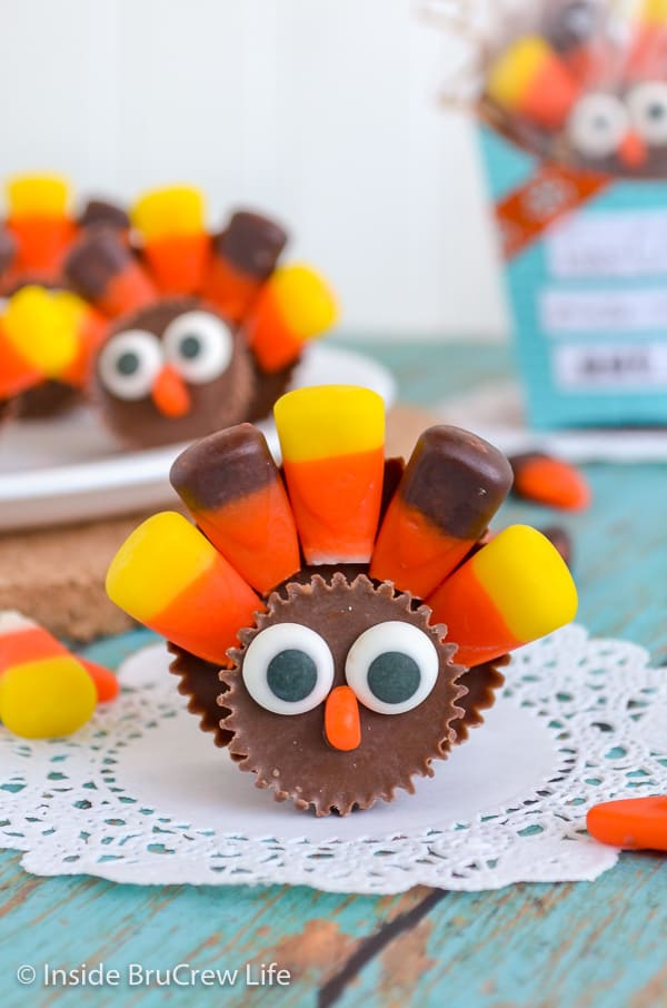 A Reese's turkey with candy corn tail standing on a white paper.