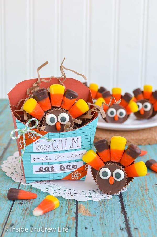 A green board with candy turkeys on it and a paper french fry box with another turkey in it.