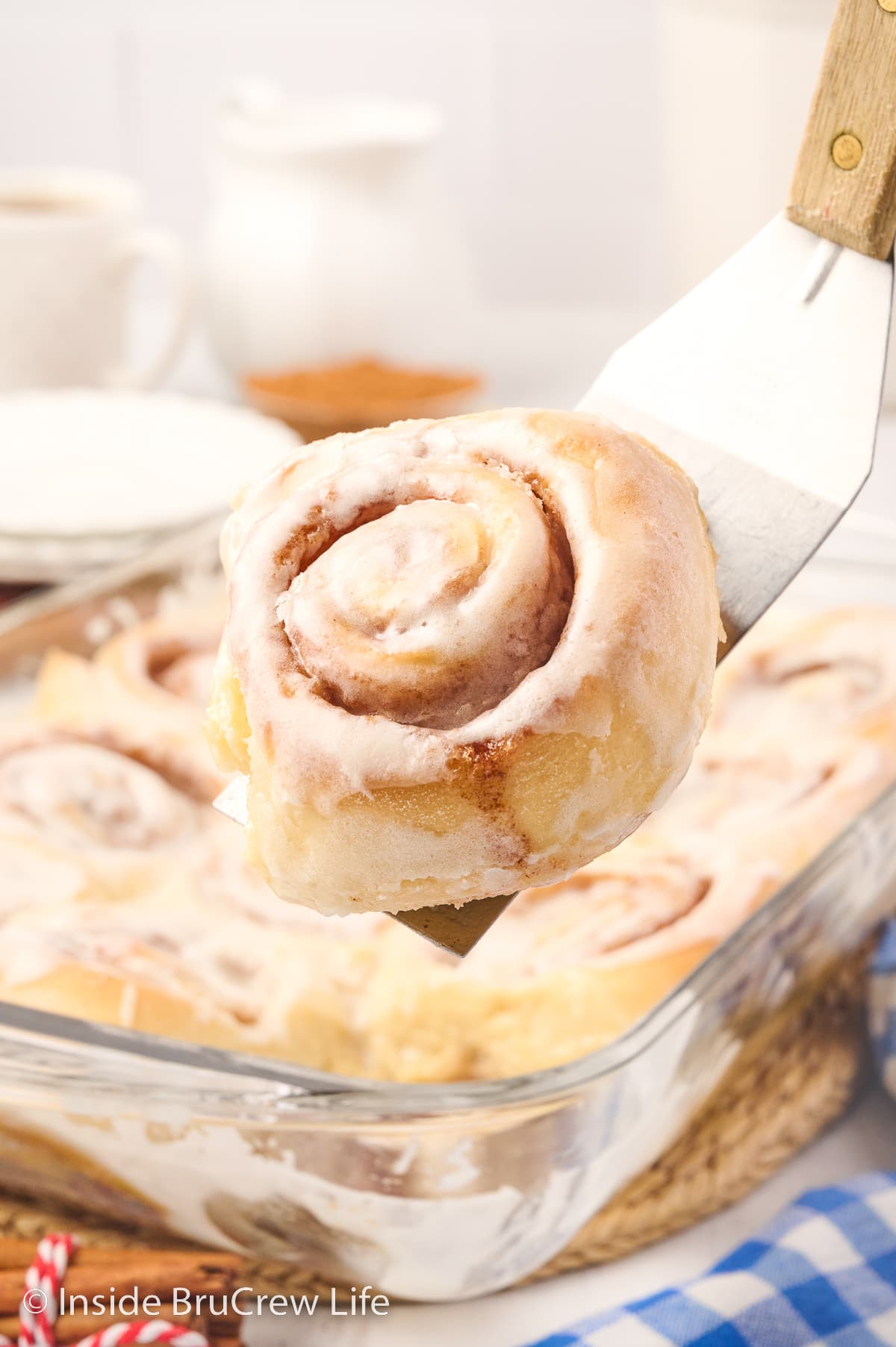 A spatula lifting a cinnamon roll out of a pan.