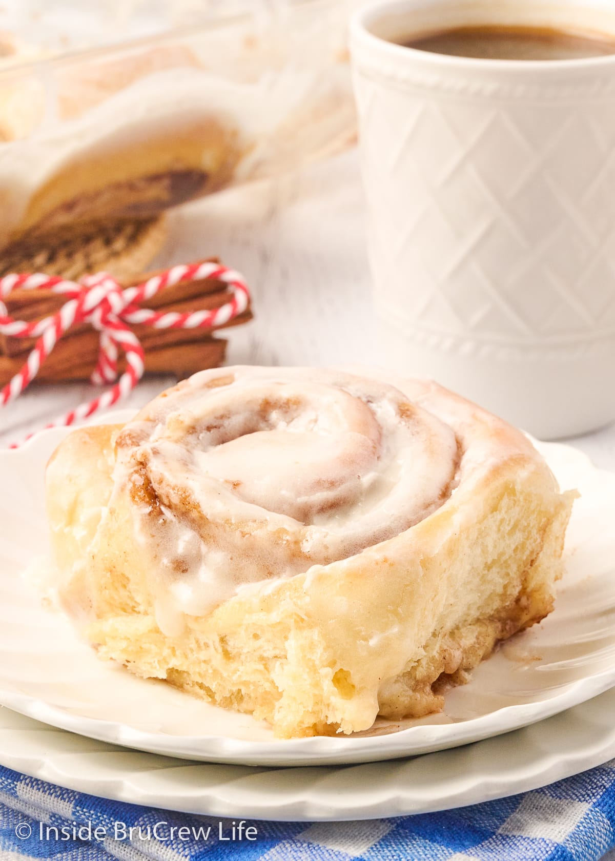 A gooey cinnamon roll on a white plate.