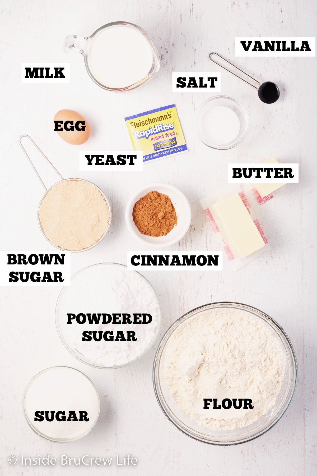 A white board with bowls of ingredients for cinnamon rolls.