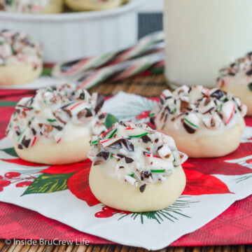 A red and white napkin with a few peppermint snowballs topped with white chocolate and candy canes.