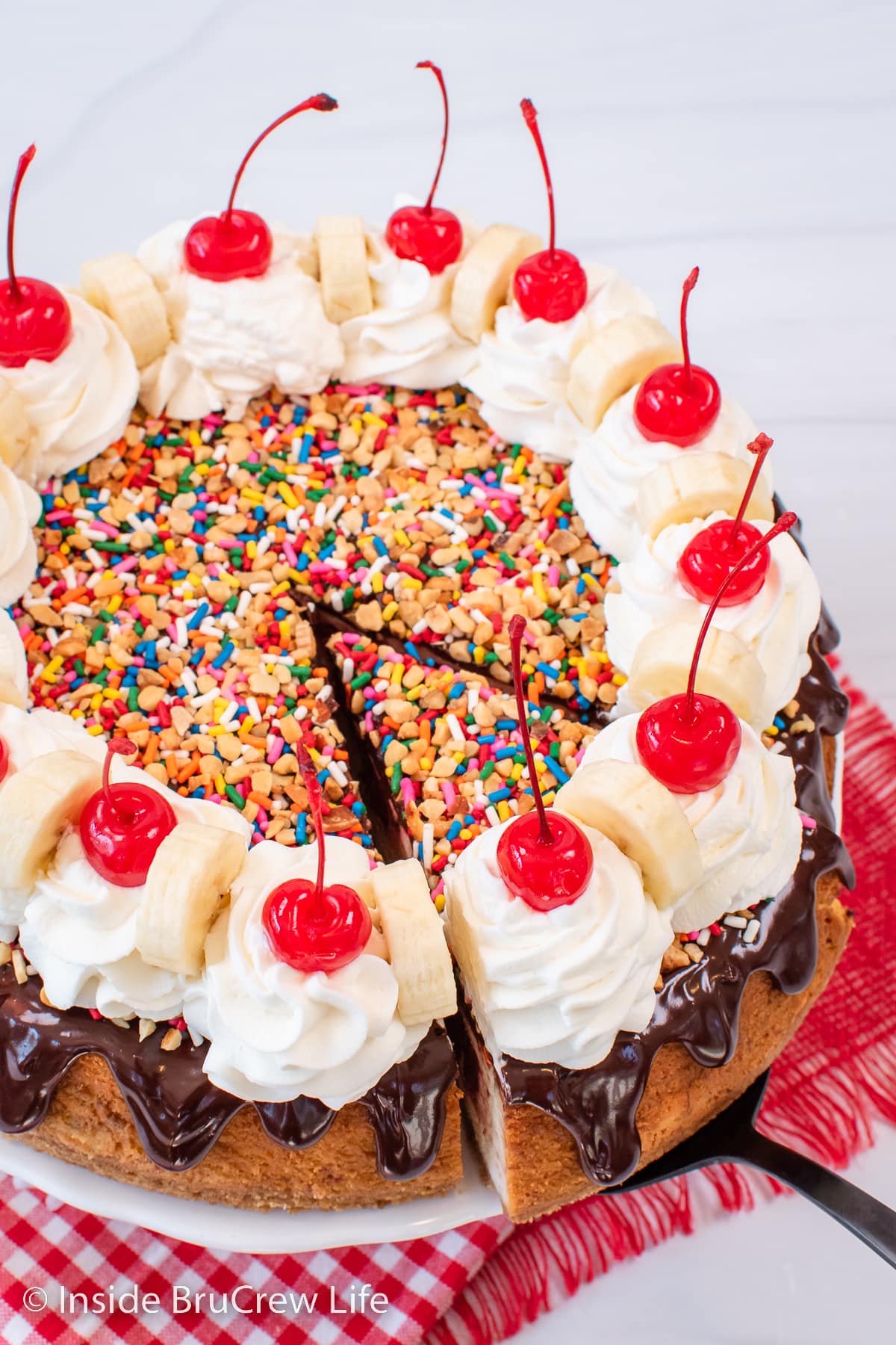 A slice of banana split cheesecake with a slice being pulled out.