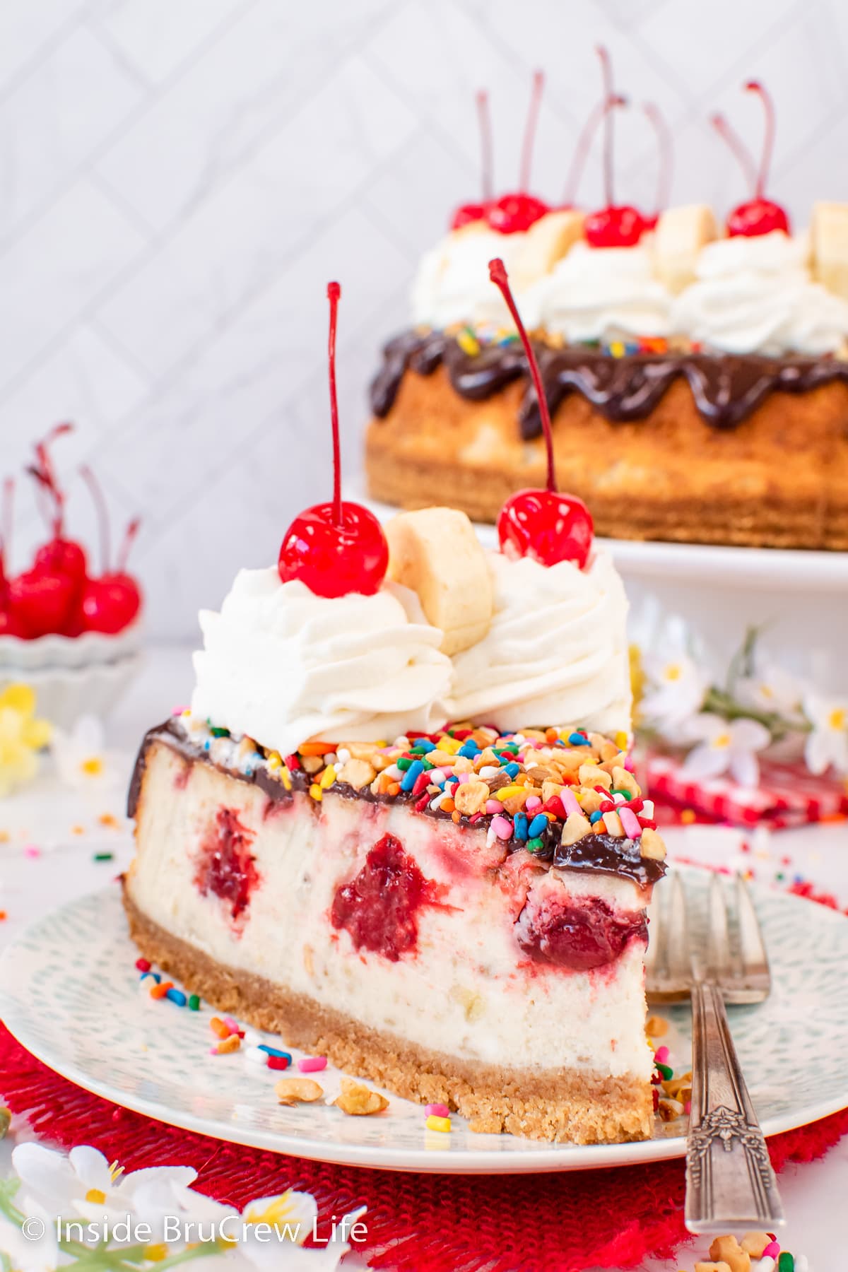 A slice of banana split cheesecake on a white plate.