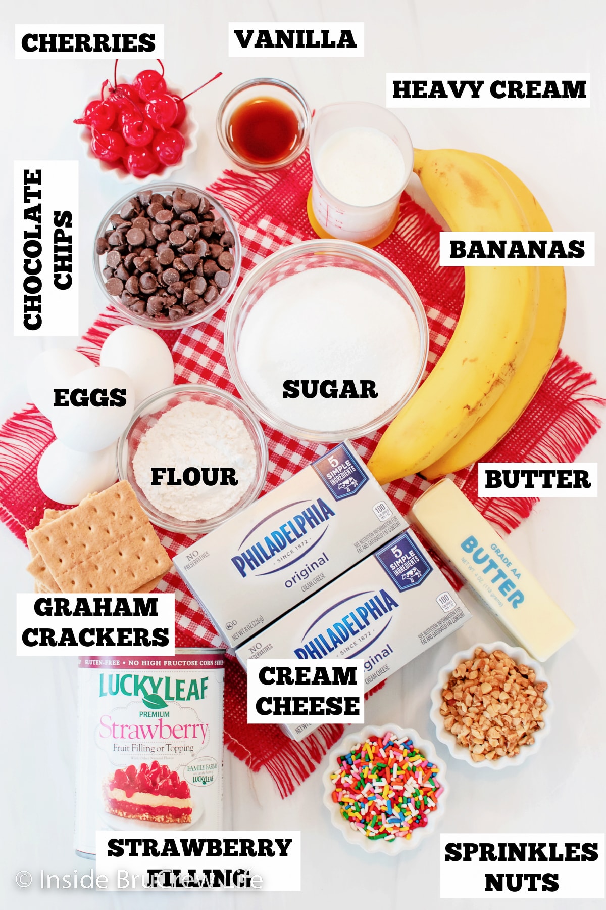 A white board with bowls of ingredients needed to make a banana split cheesecake.