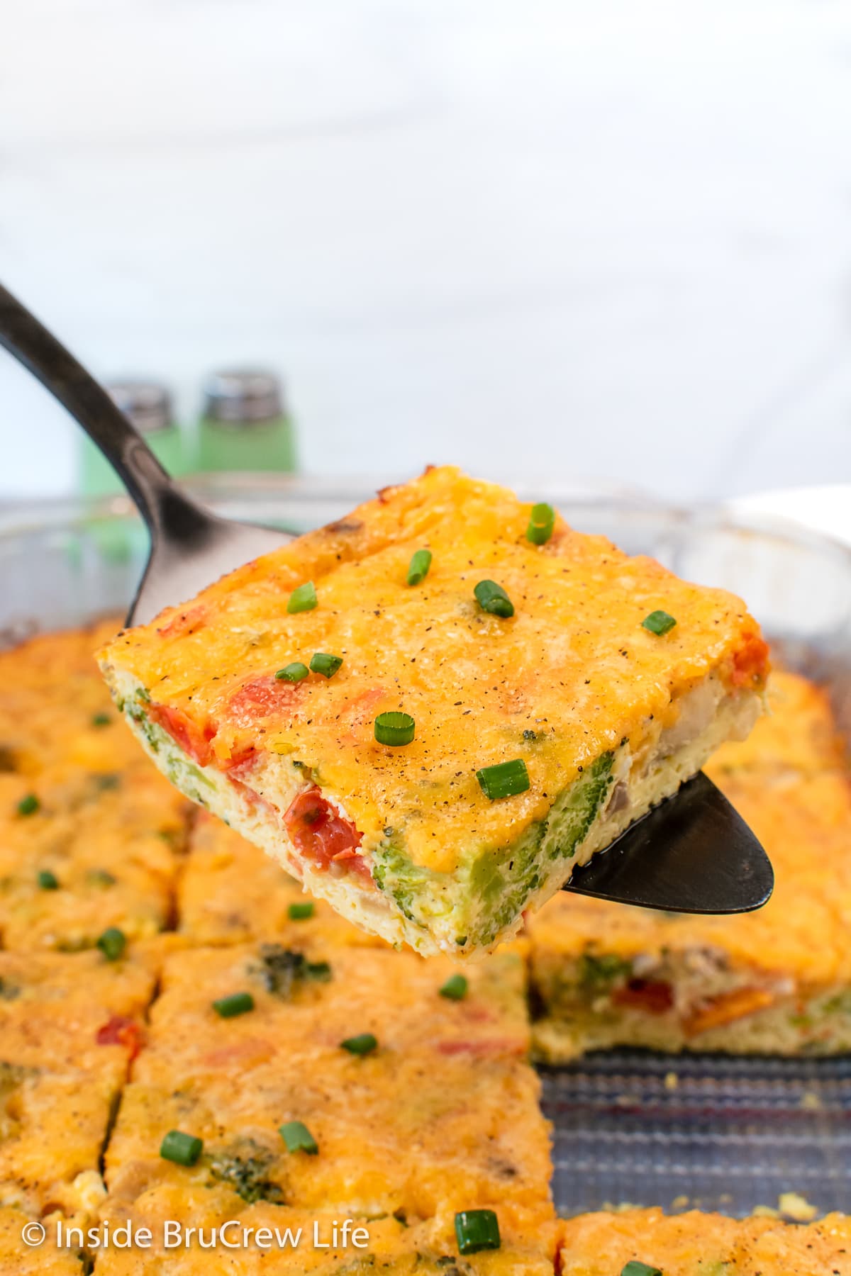 A metal spatula lifting an egg bake square out of a pan.