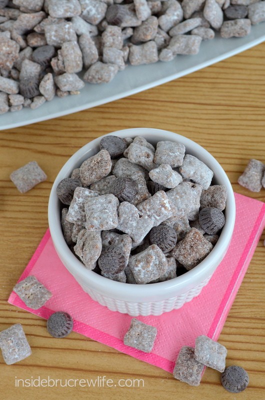 A white bowl of puppy chow with chocolates.