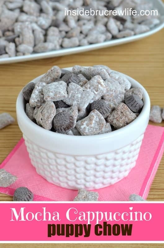 A white bowl of puppy chow with chocolate candies.