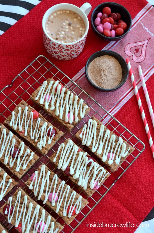 Overhead picture of a wire rack with Raspberry Hot Chocolate Granola Bars with white chocolate drizzles on it.