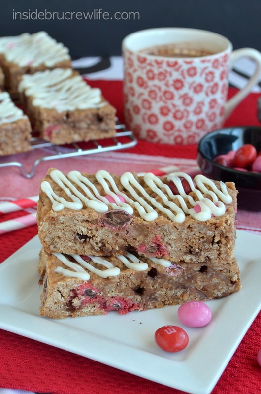 A white plate with two Raspberry Hot Chocolate Granola Bars on it and a cup of hot chocolate behind it.