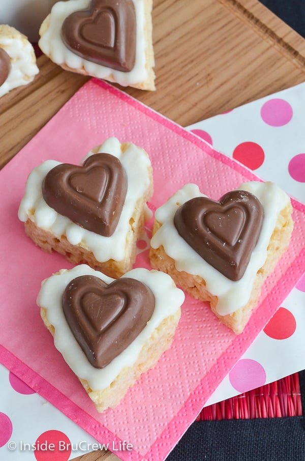 3 rice krispie treats in the shape of a heart on a pink napkin.