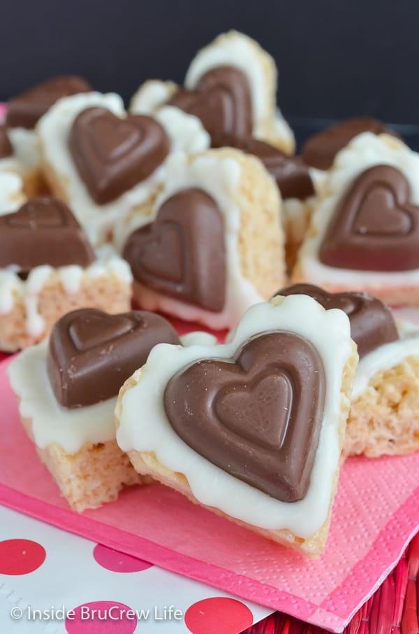 Rice krispie treats in the form of a heart with a heart chocolate candy on them.