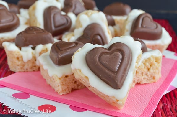 A bunch of heart shaped rice krispie treats covered in white chocolate with a candy heart.