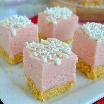 Strawberry shortcake fudge topped with white chocolate drizzles on a white plate