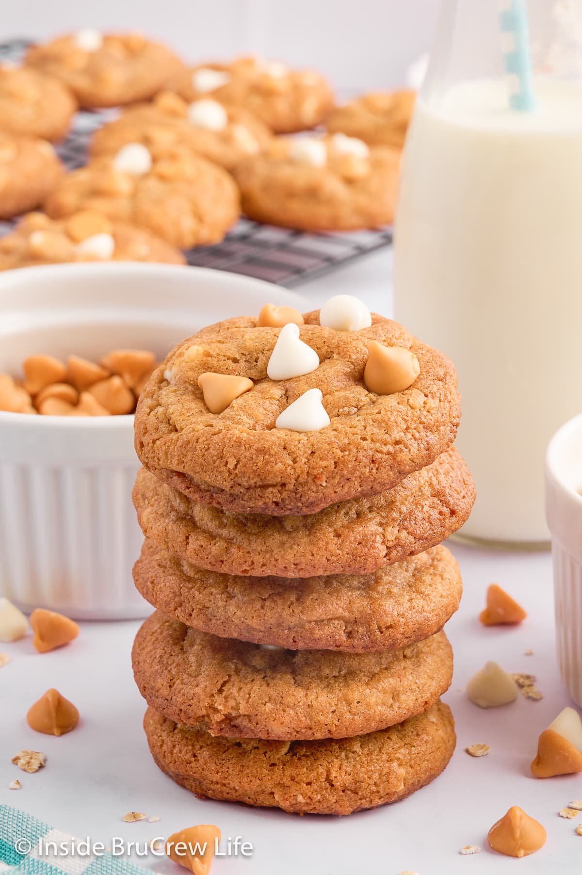A stack of cookies by a glass cup of milk.