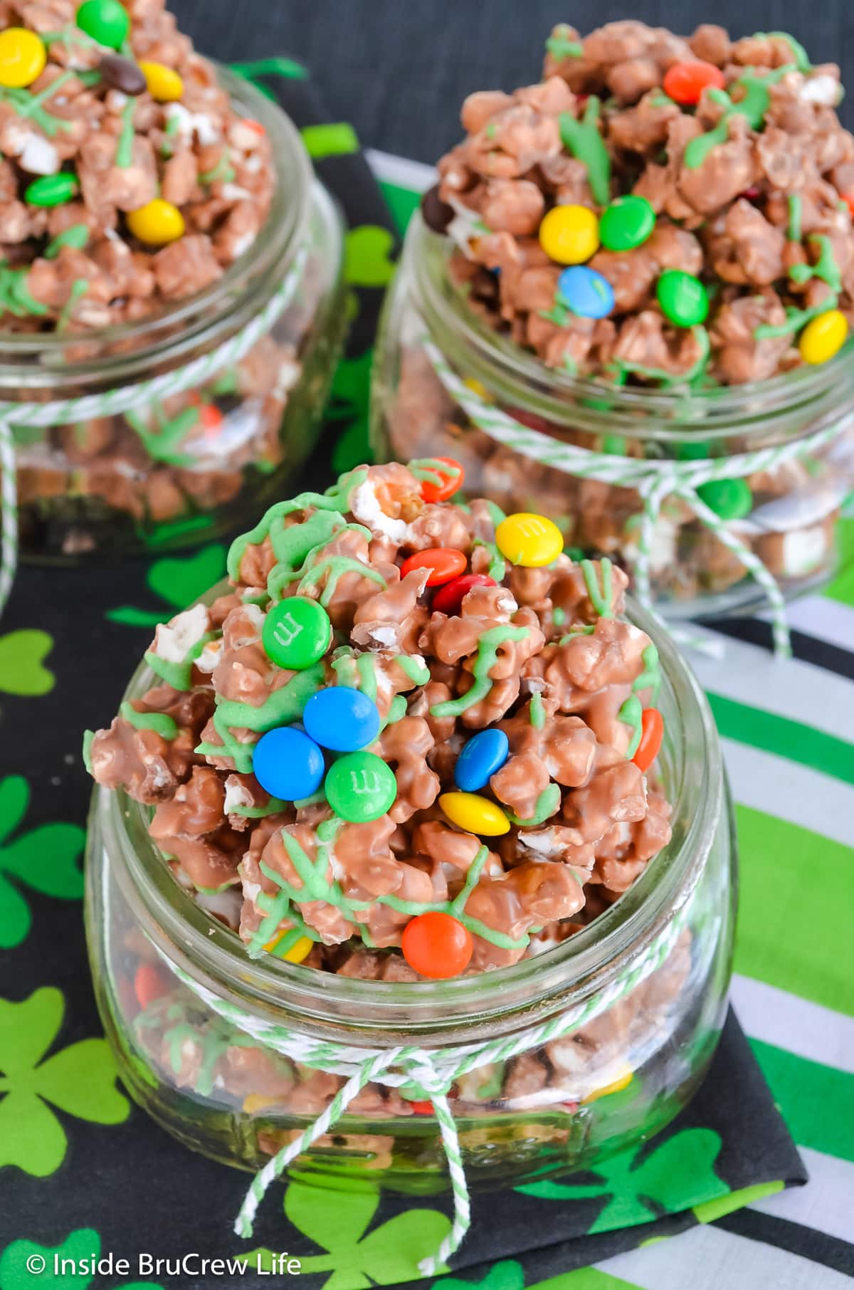 Chocolate covered popcorn with candy in glass jars.