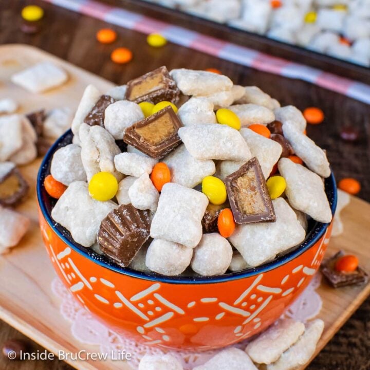 An orange bowl filled with puppy chow and Reeses's candies.