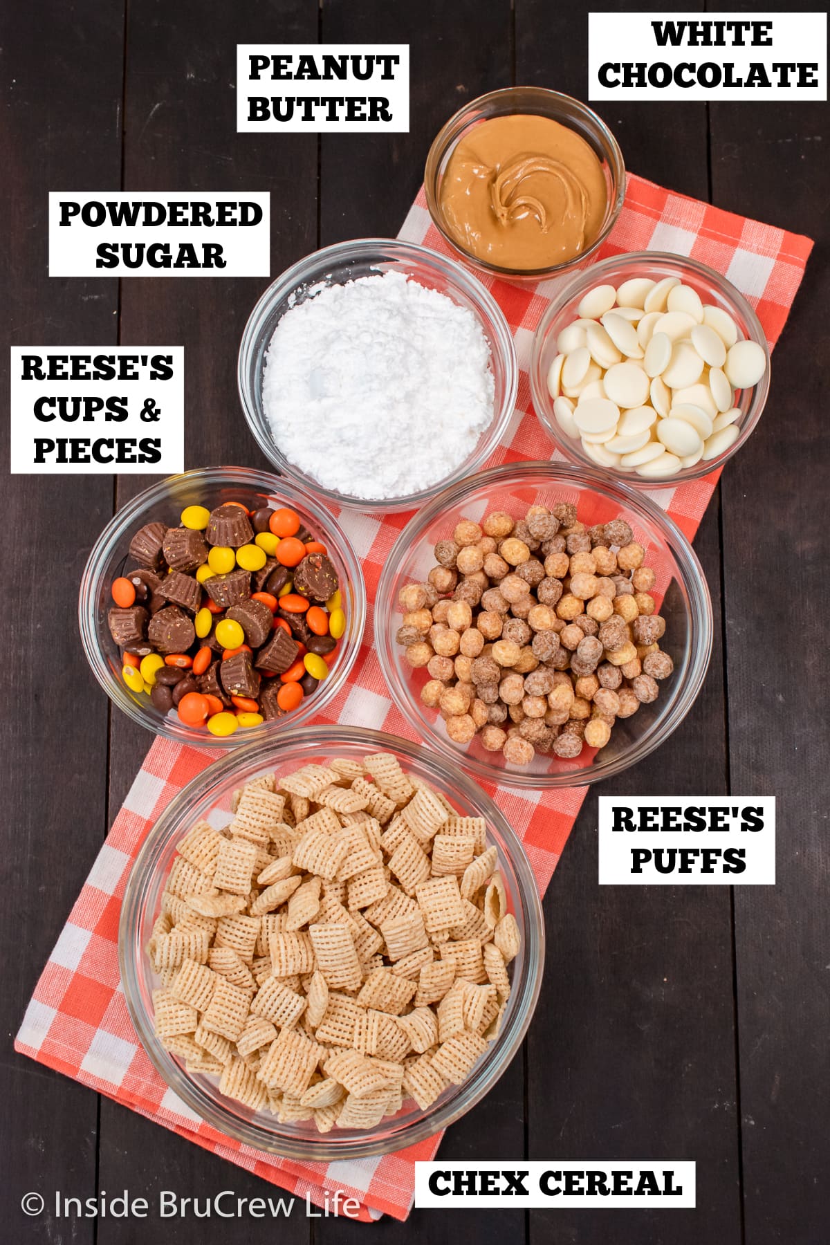 A brown board with bowls of ingredients needed to make muddy buddies with Reese's.