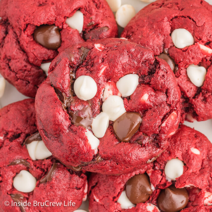 A pile of red cookies with white and dark chocolate chips on a plate.