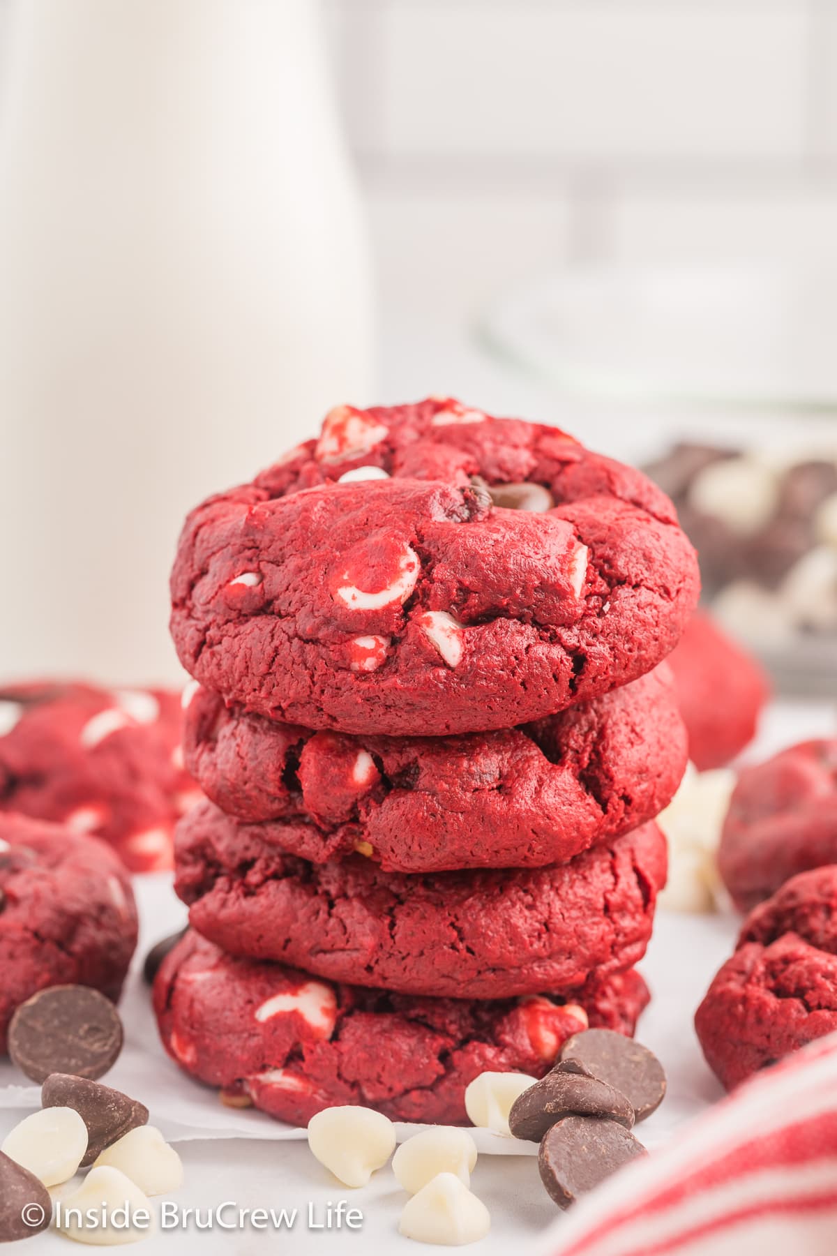 A stack of red cake cookies with a bottle of milk.