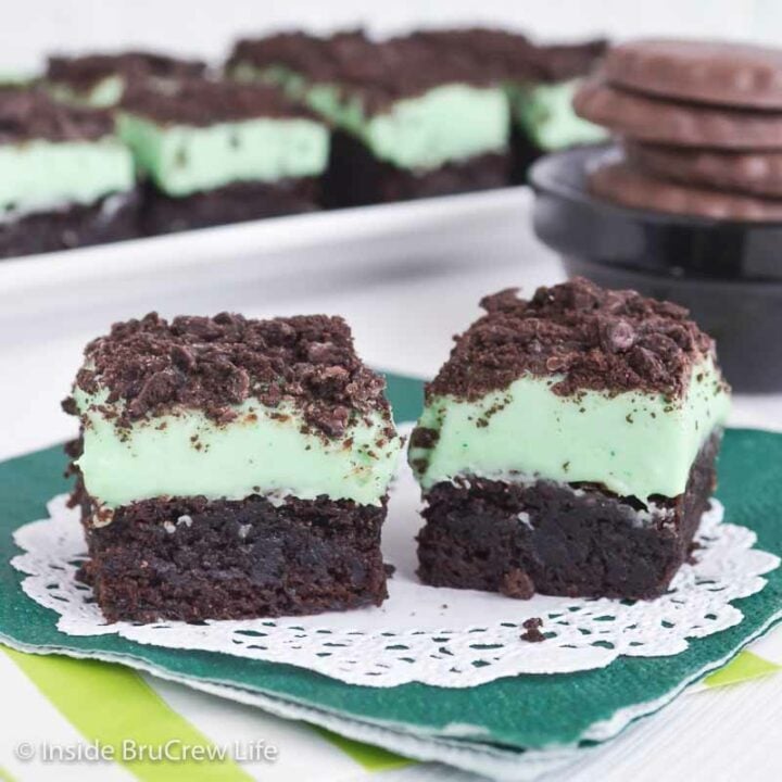 Two brownies topped with mint fudge and mint cookies.