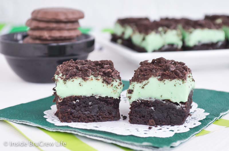 Two brownies topped with mint fudge and thin mint crumbles.