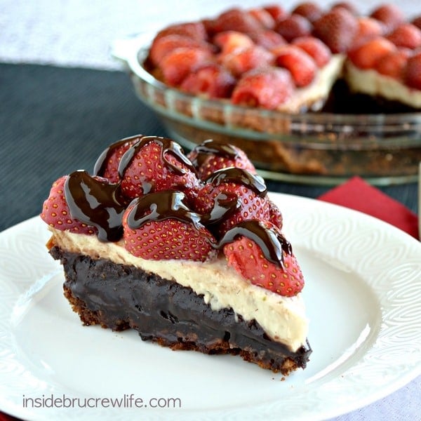 A white plate with a slice of brownie banana split pie on it.