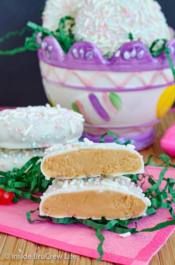 A glass Easter basket filled with cookie butter eggs and a few eggs in front cut in half showing the filling