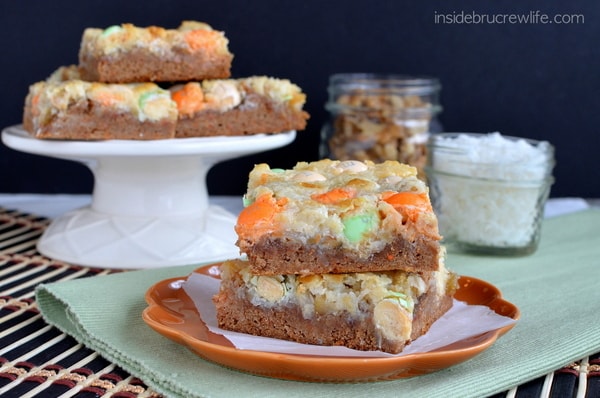 Carrot cake bars topped with green and orange candies on a dark orange plate.