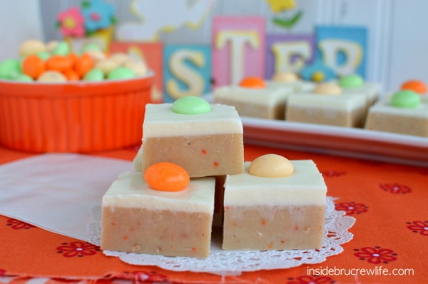 Carrot cake fudge topped with a cream cheese fudge stacked together on a white doily.