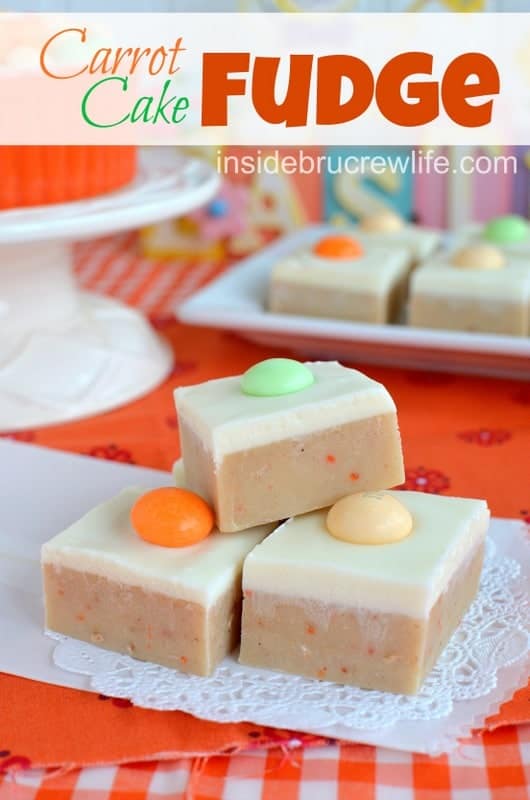 Carrot cake fudge topped with a cream cheese fudge stacked together on a white doily.