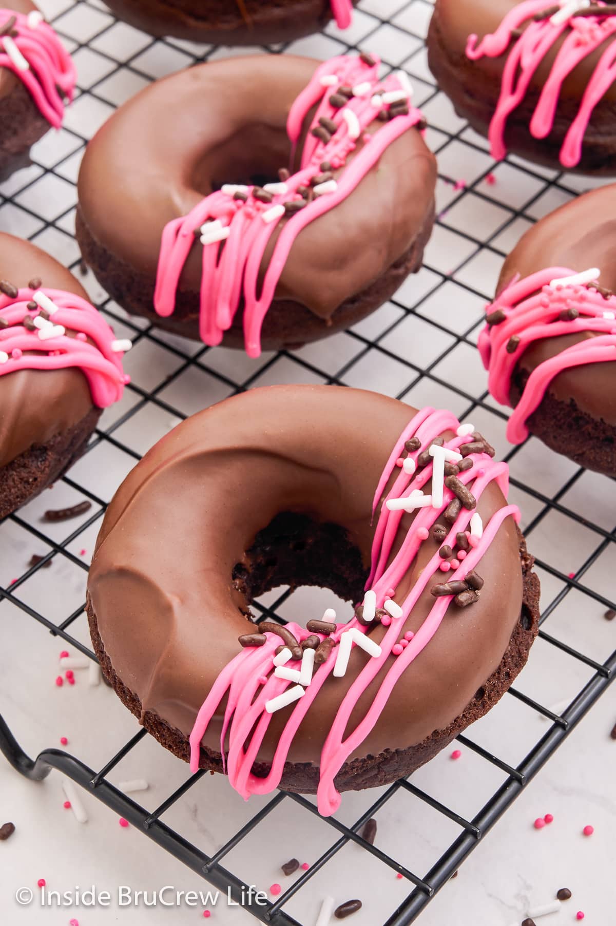 Glazed chocolate donuts on a wire rack.