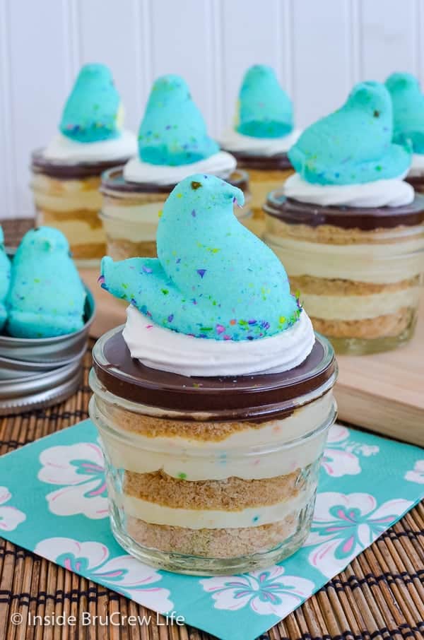 Close up picture of a blue peep sitting on a jar of eclair cake pudding with more jars in the background.