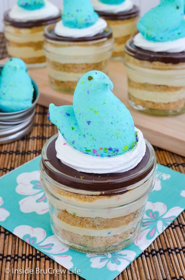A jar of eclair cake with a blue marshmallow Peep on top with more jars behind it.