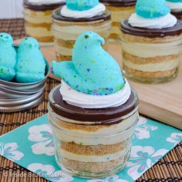 A jar of funfetti eclair cake with a blue marshmallow Peep on top and more jars behind it.