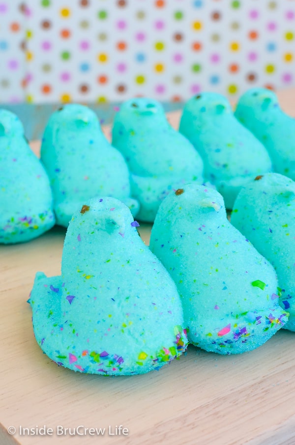Two rows of blue marshmallow Party Peeps on a wooden cutting board.