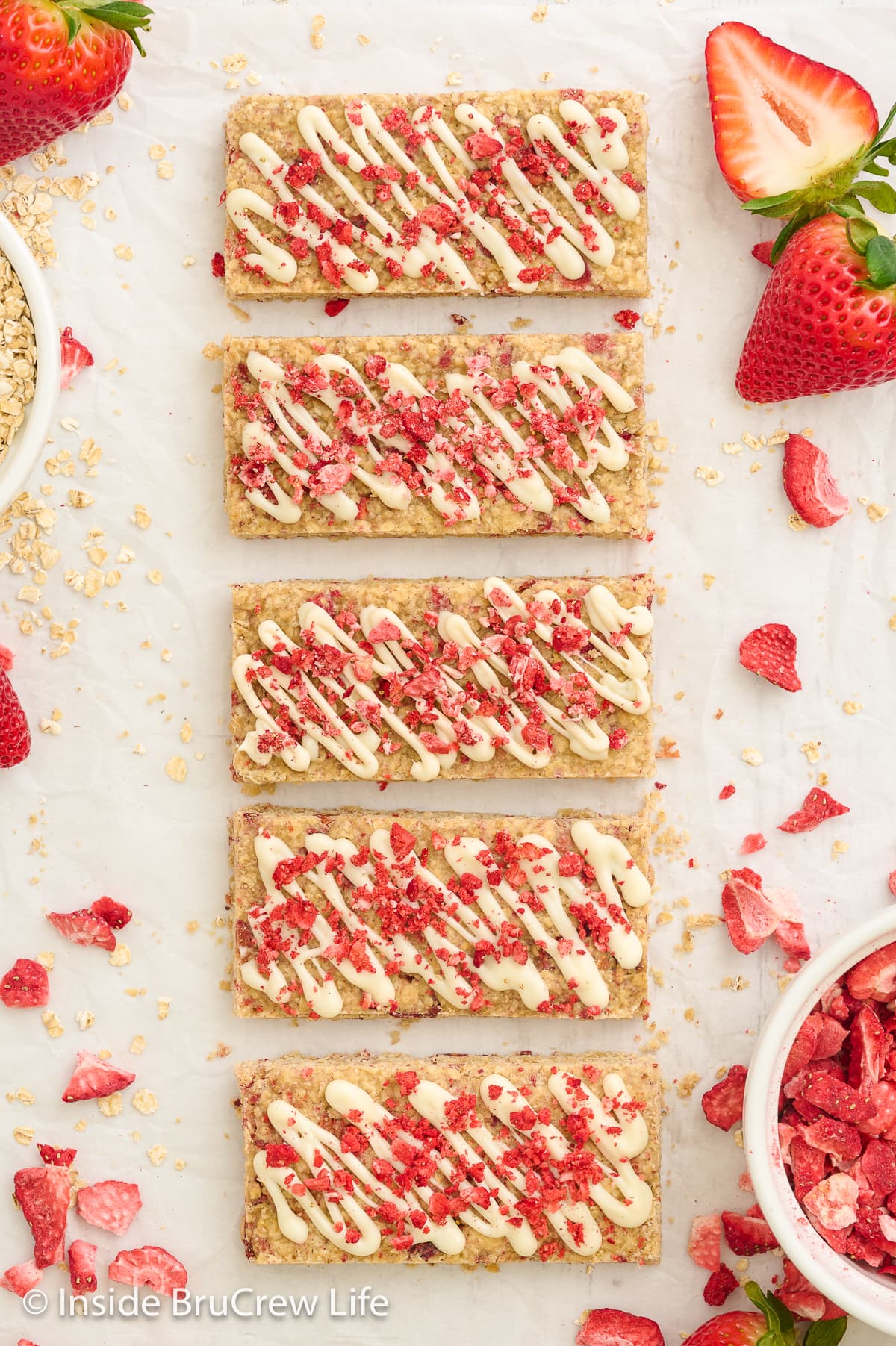 A white board with baked granola bars drizzed with white chocolate on it.