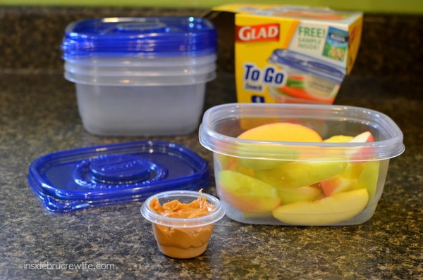 A clear plastic container with apple slices and peanut butter
