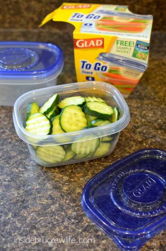 A clear plastic container filled with cucumber slices
