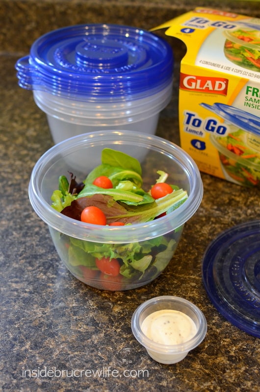 A clear plastic container filled with salad