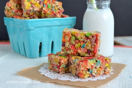 Fruity Pebbles Granola Bars stacked on each other on a white doily with a box of bars behind it