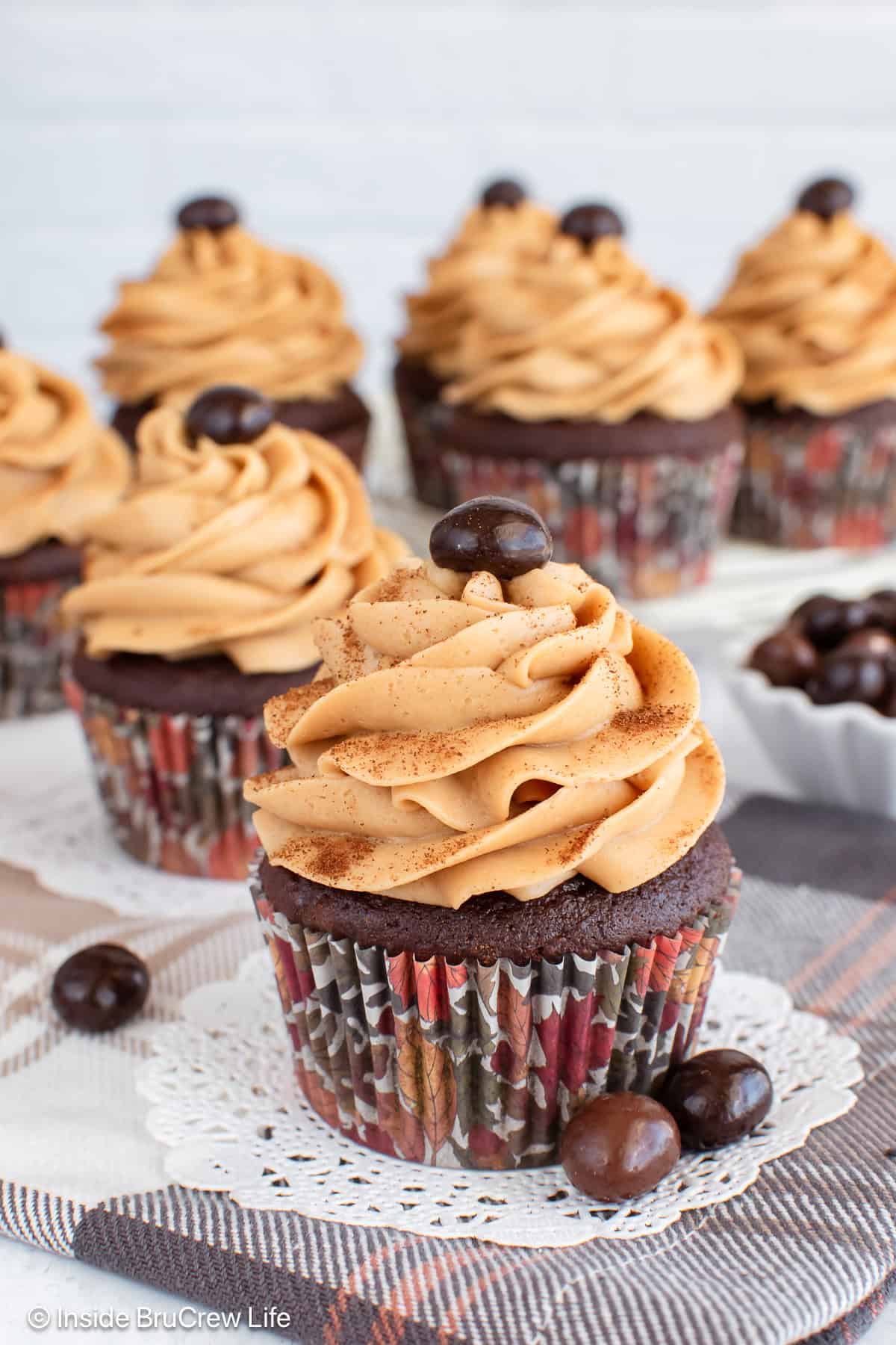 Chocolate mocha cupcakes with swirls of espresso buttercream on a board and cake plate.