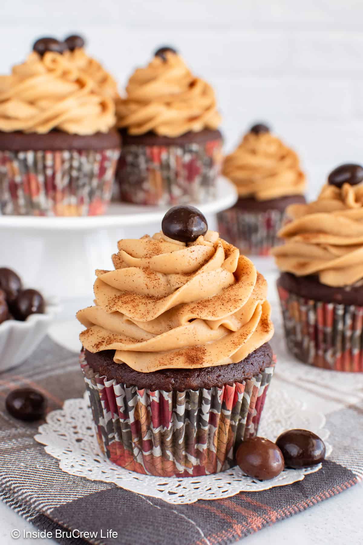 Mocha cupcakes with espresso buttercream on a board and a white cupcake stand.
