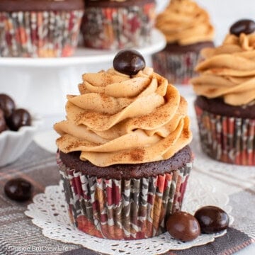 Mocha cupcakes with espresso buttercream on a white doily and brown towel.
